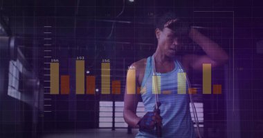 Pausing woman wearing blue tank top, fingerless gloves in gym, with jump rope and data overlay. Athletic, fitness, training, cardiovascular, strength, motivation, modern