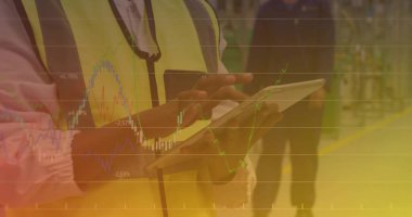 Güvenlik yeleği giyen erkek işçi bitkide dokunmatik ekran tablet kullanıyor, sarı zemin işaretli. Endüstriyel, takım çalışması, üretkenlik, güvenlik, teknoloji, lojistik, modern