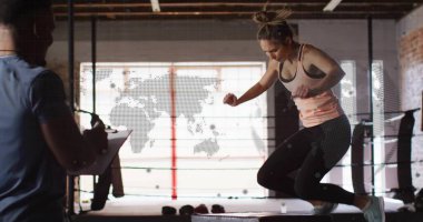 Jumping athlete clearing plyometric box in boxing ring, with trainer holding clipboard, copy space. Training, strength, power, fitness, determination, wellness, athletic