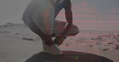 Tying runner in sportswear fastening shoelaces on running shoes along desert trail, with smartwatch. Athletic, fitness, outdoors, endurance, motivation, adventure, performance