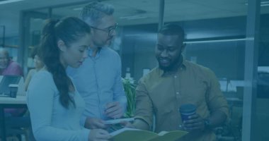 Three colleagues reviewing printed docs in workspace wearing casual attire, with coffee cup, plant. Collaboration, teamwork, professional, office environment, modern, productivity, communication