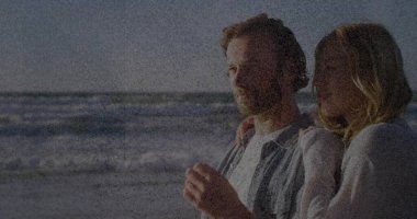 Kucaklaşan çift, kazak, gömlek, okyanus dalgaları ve fotokopi uzayı ile kumlu sahilde ufka bakıyor. Romantizm, deniz kenarı, dinginlik, bağ, eğlence, yaşam tarzı, manzara