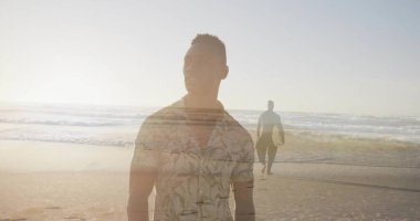 Standing man wearing palm shirt gazing at sea at sunset, surfer carrying surfboard walking shore. Coastline, sunset, reflection, ocean, adventure, leisure, lifestyle