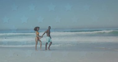 Sahilde yürüyen mutlu Afro-Amerikan çifti yerine yıldızların animasyonu. Romantik aşk, ilişki ve birliktelik kavramı dijital olarak oluşturulmuş video.