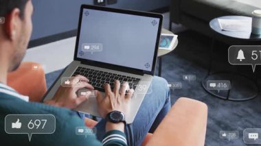 Dizüstü bilgisayarda yazan adam, sosyal medya simgeleri üretiyor. Bağlantının arttığını ve dibe vurduğunu gösteriyor. Teknoloji, sosyal medya, dijital etkileşim, çalışma alanı, modern iletişim, bağlantı