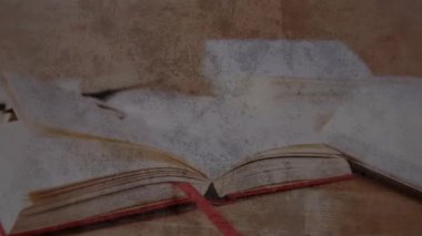 Kırmızı kurdeleli açık bir kitabı süpürüp duran hafif bir esinti sayfaların ahşap masada kanat çırpmasına neden oluyor. Edebiyat, okuma, çalışma, parşömen, antika, klasik, akademik