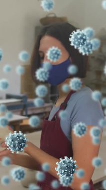 Kil tutan yüz maskesi takan kadın çömlekçiye karşı yüzen Covid-19 hücrelerinin birleşik videosu. Çömlekçilik ve covid-19 salgın konsepti