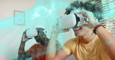 Oyun oynamak için kanepede VR kulaklıklarını kaldıran arkadaşlar, dönen parlak deniz mavisi parçacıklarını aktifleştiriyorlar. Sanal gerçeklik, oyun, teknoloji, eğlence, sürükleyici, sosyal etkileşim, modern