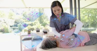 Physical therapist aligning patient on table activating data holograms for shoulder mobilization. Medical, therapy, wellness, technology, outdoor, relaxation, rehabilitation