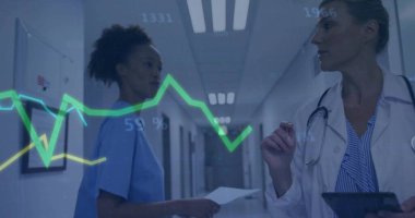 Reviewing nurse and doctor in medical attire analyzing line graph in hospital corridor, with tablet. Healthcare, collaboration, diagnostics, technology, professional, clinical, innovation