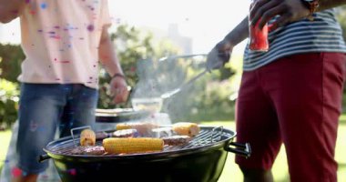 Izgara ikilisi yemek pişirmeye maşa alarak ve arka bahçedeki yemek hazırlıkları için köfte çevirerek başlıyor. Barbekü, açık hava, kutlama, yaz, neşe, eğlence, doğa.