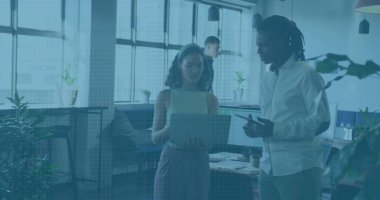 Discussing woman holding laptop with coworker at office, with smartphone coffee cup and notebooks. Collaboration, teamwork, innovation, modernity, productivity, workplace, technology