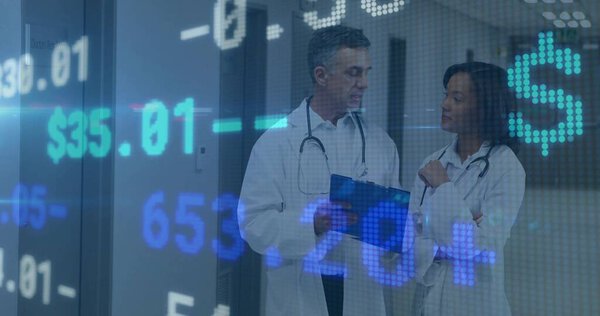 Two physicians reviewing financial data overlay in hospital hallway, with clipboard, stethoscopes. Medical, professional, digital, innovation, collaborative, healthcare, analysis