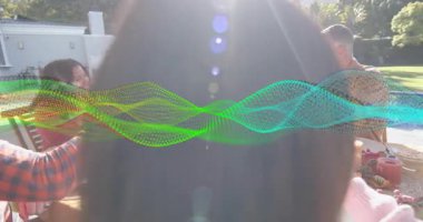 Uzun saçlı bir kadın, cam kıvılcımlar saçan bir gruba uzanıyor ve masada yemek yerken meyve suyu içiyor. Kutlama, neşe, dostluk, açık hava, toplumsal yaşam tarzı, mutluluk.