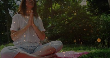 Oturan kadın göğsünü çimlerin üzerinde katlıyor, pembe yoga minderiyle, süzülen güneş parçacıklarıyla. Dinginlik, sağlık, meditasyon, doğa, sükunet, farkındalık, açık hava