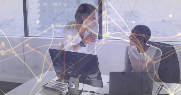 Collaborating two mid adult women analyzing network data at modern office, with desktop monitor. Professional, teamwork, analytics, urban, business, innovation, digital