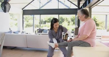 Terapist diz çöküyor, ellerini bacağının altına koyuyor, kaldırıyor, kaçırıyor, direniyor ve terapi için alçaltıyor. Rehabilitasyon, fizik tedavi, sağlık, refah, hareket, profesyonel, klinik