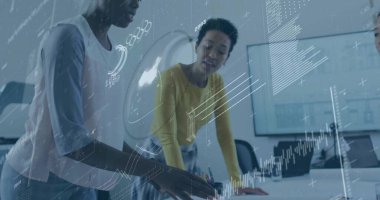 Masaya yaslanmış, iş kıyafeti giymiş iki meslektaş monitörlerdeki verileri dizüstü bilgisayarla inceliyor. İşbirliği, takım çalışması, veri analizi, modern çalışma alanı, profesyonel, üretkenlik, yenilik