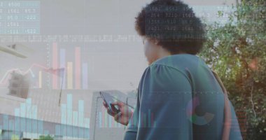 Holding smartphone, midadult woman viewing financial charts at glass office building, copy space. Business, finance, technology, professional, businesswoman, innovation, urban