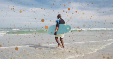 Walking senior surfer carrying blue surfboard into shallow shoreline with leash and orange spots. Ocean, shoreline, leisure, serenity, aquatic, adventure, vibrant