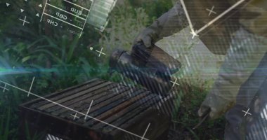 Arı kovanında kovan çerçeveli sigara içen koruyucu giysiler giyen duman arıcısı üretiyor. Kırsal, işçilik, sürdürülebilirlik, doğa, hobi, açık hava, geleneksel