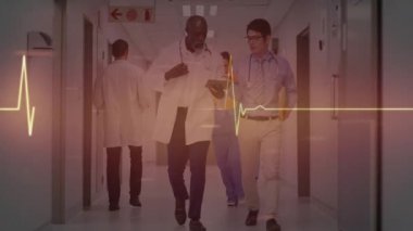 Hastane koridorunda yürüyen erkek doktorlar hasta incelemesi için EKG senkronizasyonunu etkinleştiriyor. Sıhhiye, işbirliği, profesyonel, sağlık, teknoloji, tanı, takım çalışması