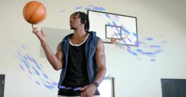 Male athlete spinning basketball on finger, tucking arm as graphics swirl around hoop for fitness. Sports, fitness, athleticism, energy, motion, training, urban