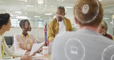 Man in mustard jacket addressing business meeting revealing animated icons showing strategy points. Collaboration, teamwork, innovation, corporate, strategy, presentation, modern