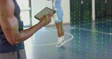 Koç, basketbol talimindeki ilerlemeyi takip etmek için dijital tablete tıklıyor ve zıplayan oyuncuları kaydediyor. Eğitim, performans, analitik, atletizm, takım çalışması, motivasyon, koçluk