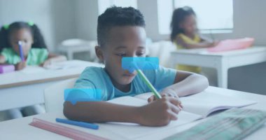 Yeşil kalemle not defterine yazan erkek öğrenci. Öğrenmek için kafasının etrafında kabarcıklar çıkıyor. Eğitim, sınıf, iletişim, teknoloji, odaklanma, yaratıcılık, işbirliği