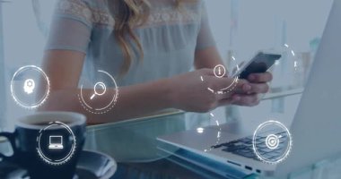 Masasında oturmuş akıllı telefonları dinleyen bir kadın dizüstü bilgisayar yönetim araçlarının üstündeki teknoloji simgelerini canlandırıyor. Teknoloji, yenilik, dijital, iletişim, çalışma alanı, modern, üretkenlik