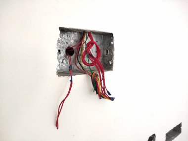 Beyaz tuğla duvardaki bitmemiş çelik bağlantı kutusu. Ev yapımı elektrik tesisatı, ev kablosu tamiri. Evdeki güç sistemini güncelle. Kablolar, anahtar kutusu ve prizler..