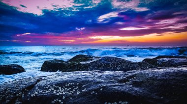 Sahilde güzel bir güneş doğuyor. Gün doğumunda Hindistan 'daki Rocky Beach' ten hareketli elementler ve dalga fotoğrafçılığı. Bengal körfezinde kızıl gökyüzü, yavaş çekim yapan deniz dalgaları ve kayalar..