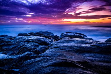 Sahilde güzel bir güneş doğuyor. Gün doğumunda Hindistan 'daki Rocky Beach' ten hareketli elementler ve dalga fotoğrafçılığı. Bengal körfezinde kızıl gökyüzü, yavaş çekim yapan deniz dalgaları ve kayalar..