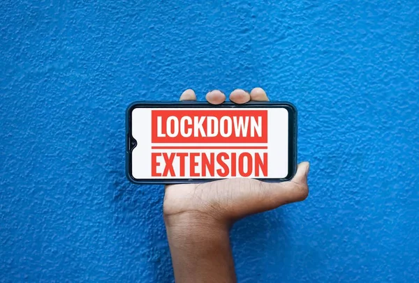 Lock Down Extension word on mobile screen isolated on blue background with copy space for text. Person holding mobile on his hand and showing front of the screen wording Lock Down Extension.