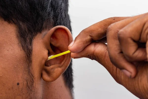 Remove Ear wax Safely - Man cleaning ear with cotton swabs closeup shot. Cleaning ear with cotton bud Dirty ear. Removing ear wax using cotton bud on white with copy space text - Concept healthy care