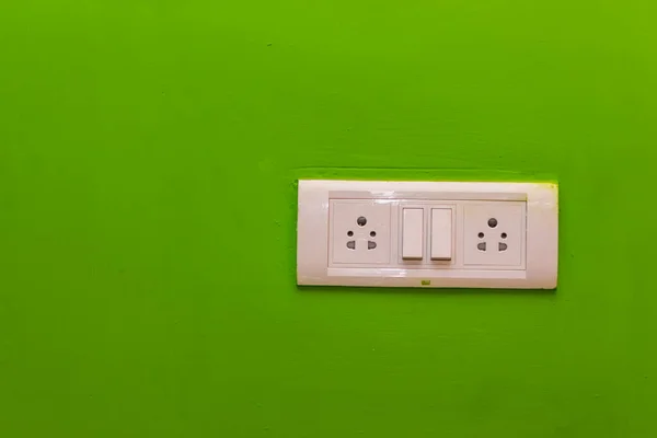 Double Sockets for electrical appliances on a green wall background. all purpose switch on a wall socket.