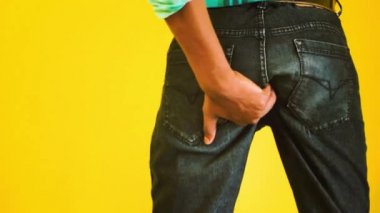 Itching buttocks - Causes of butt rashes in adults . Young man rude scratches his buttocks indoor - NOT something to do in outside public places. Itching the Buttocks, Healthcare Concept.