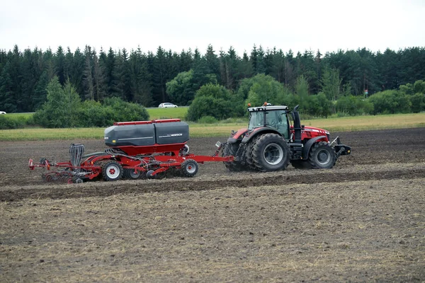 畑を耕す農家畑で耕すトラクター農場で耕すトラクターと耕す赤い農場トラクター リトアニア — ストック写真