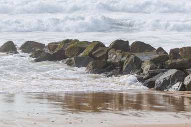 Frances Atlantik kıyısındaki Lacanau 'da bir dalgakıran. Yosun kaplı kaya ve dalgalar kıyı şeridini erozyondan korur, canlı renkler ve dokularla doğal bir deniz manzarası yaratır.