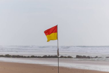 Fransa 'nın Lacanau plajında belirlenmiş bir yüzme alanı olduğunu gösteren kırmızı ve sarı bir güvenlik bayrağı. Cankurtaranlar tarafından Atlantik Okyanusu kıyısı boyunca yüzücüler için güvenli bölgeleri belirlemek için kullanılır.