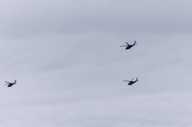 Üç askeri helikopterden oluşan bir oluşum bulutlu gökyüzünde Polonya üzerinde uçuyor. Savunma güçlerinin çarpıcı bir gösterisi ve havacılık teknolojisinin gücü