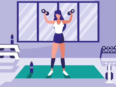 Genç atletik kadın spor salonunda dambılları kaldırıyor.