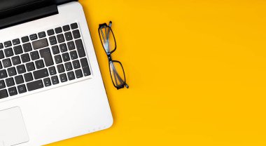 Düz dizüstü bilgisayar, sarı arka planda. Tasarım veya metin için boş alanı olan günlük çalışma alanı