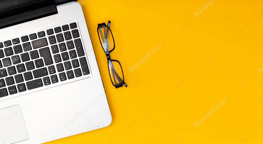 Flat lay of laptop in yellow background. Blogger workspace with blank space for design or text
