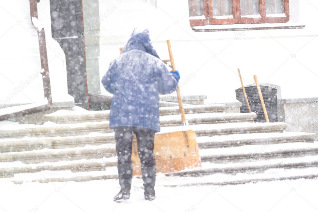 One women shovelling snow in the snowstrom. Cleaning stairs