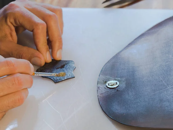 Handmade handicraft leather bag sewing process. Leather workshop smear glue