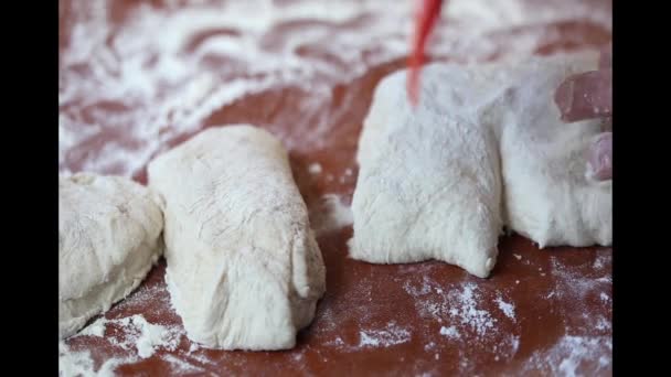 Les mains de l'homme divisant la pâte à pain par grattoir de silicium orange de cuisine sur la table — Video