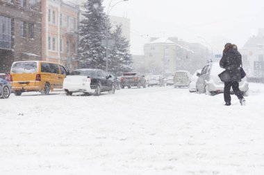 Şiddetli kar fırtınasında yetişkin bir adam kış şehir yolunu geçiyor..