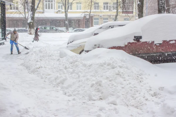 Macchina nella neve. Auto parcheggiata vicino a casa parcheggiata nella neve. Donna pulizia neve. — Foto Stock